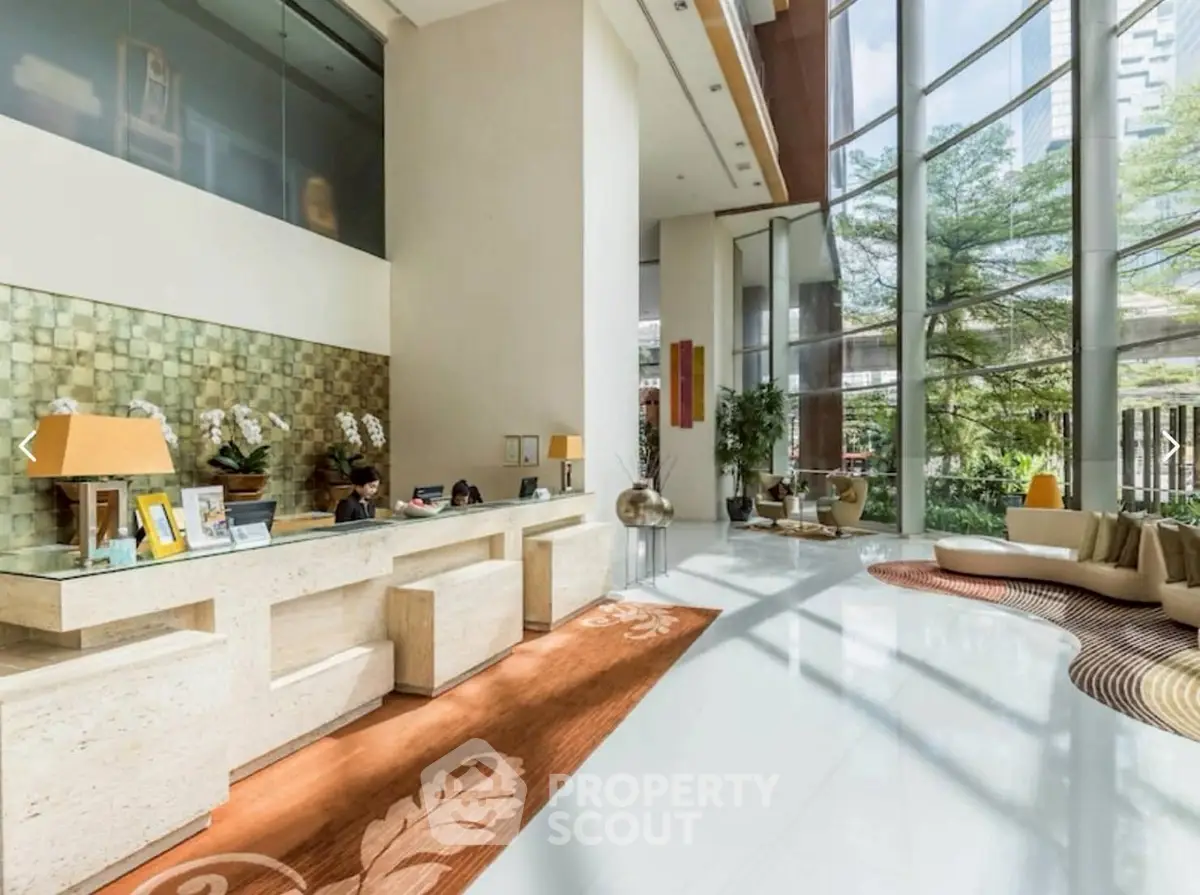 Luxurious building lobby with modern design and floor-to-ceiling windows offering lush garden views.