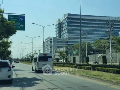 Modern hospital building with street view and vehicles in foreground