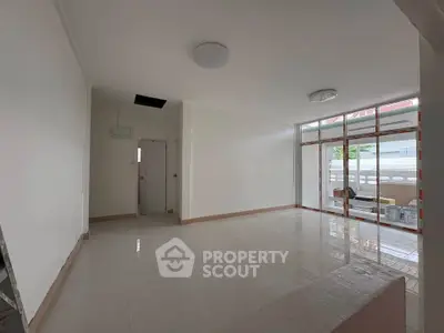 Spacious living room with large windows and glossy tiled floors