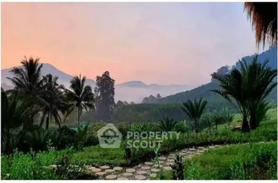 Stunning landscape view with lush greenery and distant mountains at sunrise, perfect for serene living.