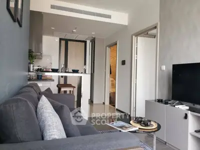Modern living room with sleek design and open kitchen layout, featuring a cozy gray sofa and stylish decor.