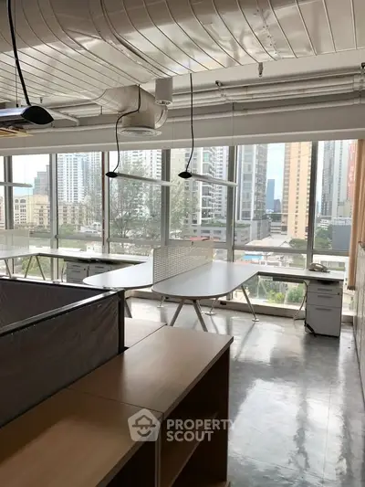 Modern office space with large windows and city view, featuring sleek furniture and open layout.