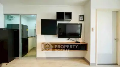Modern living room with wall-mounted TV and sleek storage units, adjacent to a kitchen with sliding glass door.