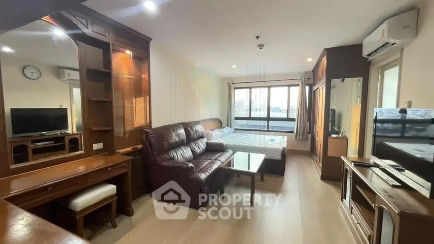 Spacious studio apartment with elegant wooden furniture and city view balcony.