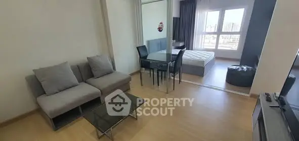 Modern open-plan living room with cozy sofa and dining area, leading to a bright bedroom.