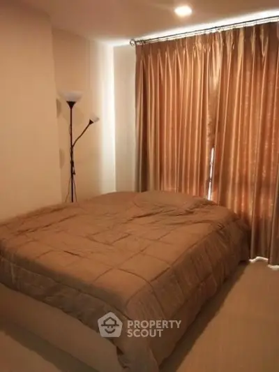 Cozy bedroom with warm lighting and elegant curtains, perfect for relaxation.