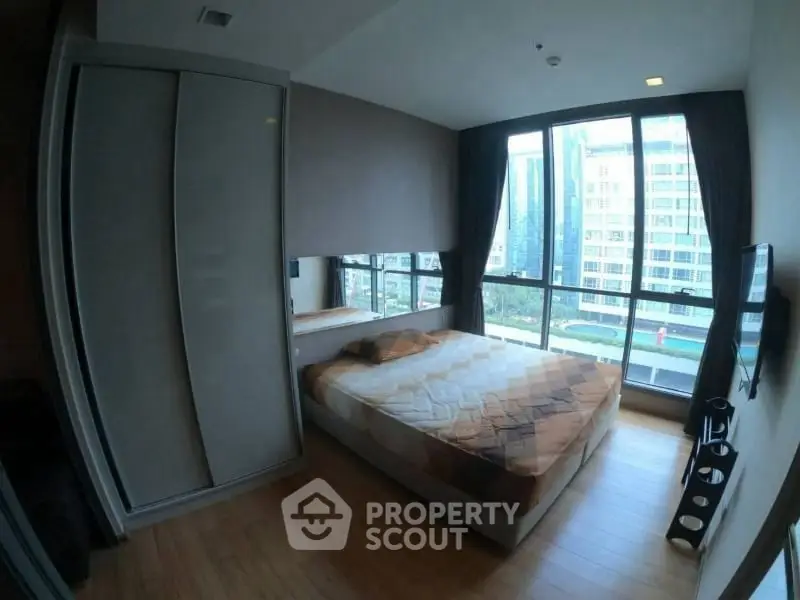 Modern bedroom with large windows and city view in high-rise apartment