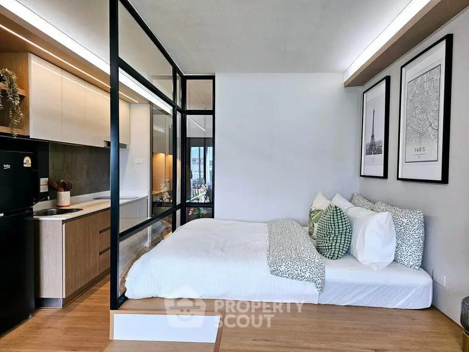 Modern studio apartment with open layout, featuring cozy bedroom and sleek kitchen design.