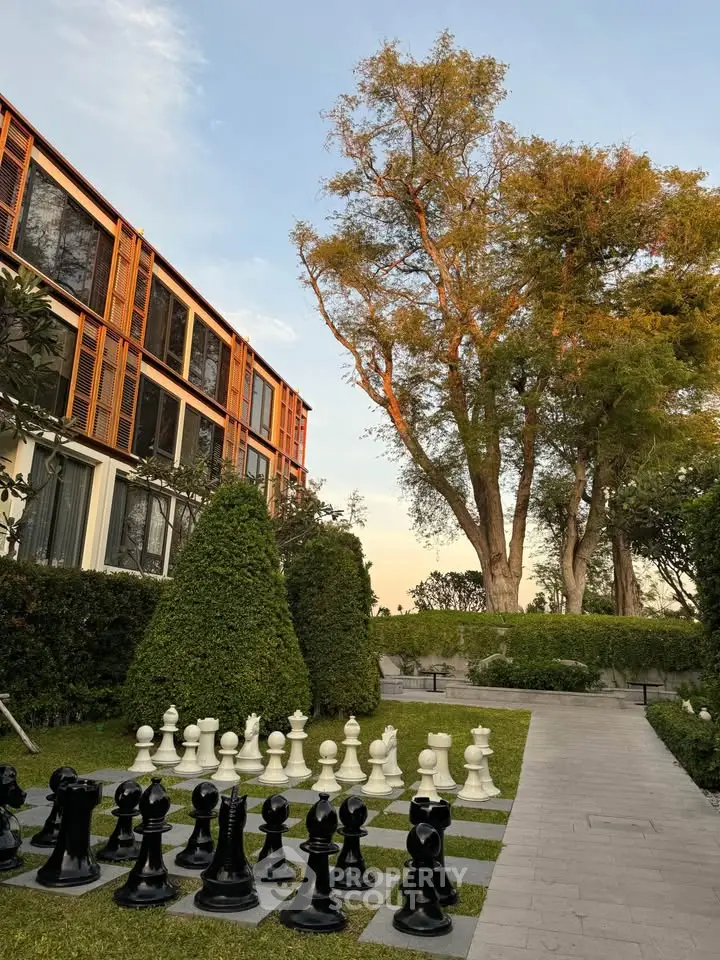 Luxurious garden with giant chess set and modern building facade, perfect for relaxation and leisure.