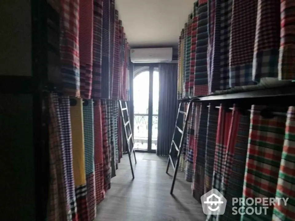 Unique hostel-style bedroom with multiple bunk beds and colorful curtains near a window.