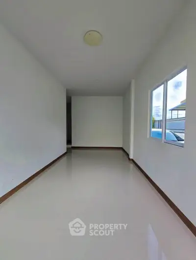 Spacious empty room with large window and glossy floor, perfect for customization.