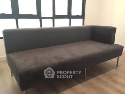 Modern minimalist sofa in a bright living room with large windows.