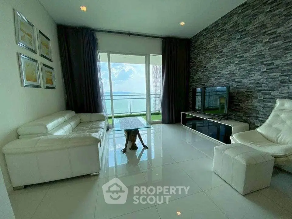 Luxurious living room with modern decor and stunning ocean view from large windows.