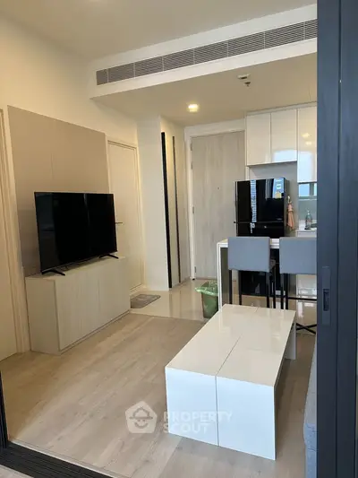 Modern living room with sleek furniture and open kitchen layout in a stylish apartment.