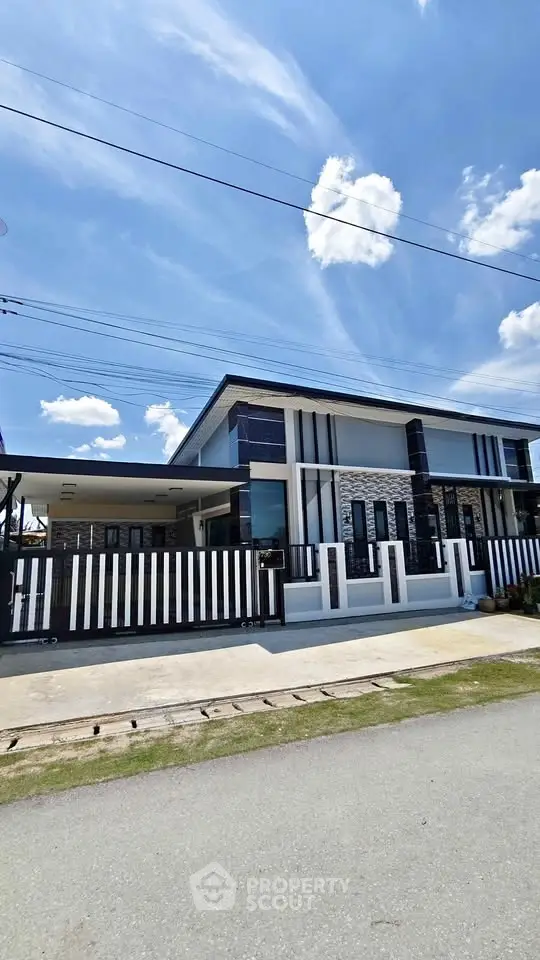 Modern two-story house with sleek design and spacious driveway under a clear blue sky.