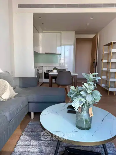 Modern living room with open kitchen, stylish decor, and cozy seating area in a contemporary apartment.
