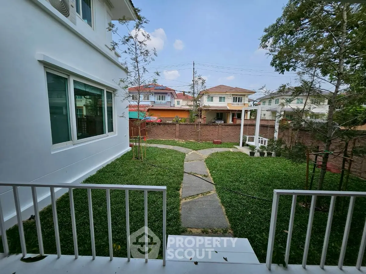 Charming suburban garden view with lush greenery and modern white house exterior.