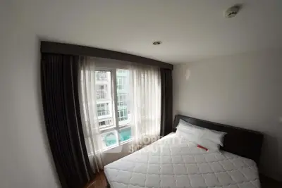 Cozy bedroom with large window and modern decor in a high-rise apartment.