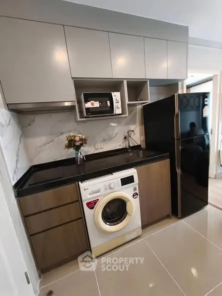 Modern kitchen with sleek cabinets, washing machine, and black fridge