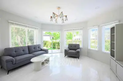 Bright and spacious living room with modern furniture and large windows offering garden views.