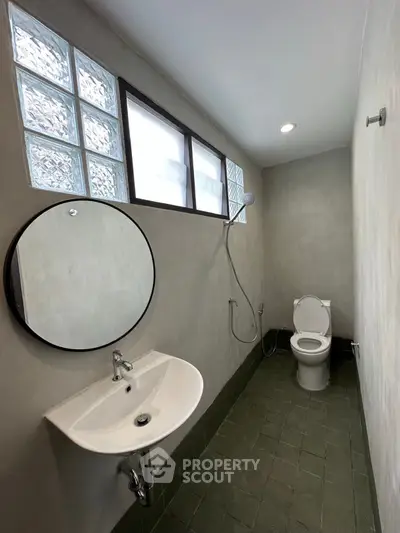 Modern minimalist bathroom with round mirror and glass block windows