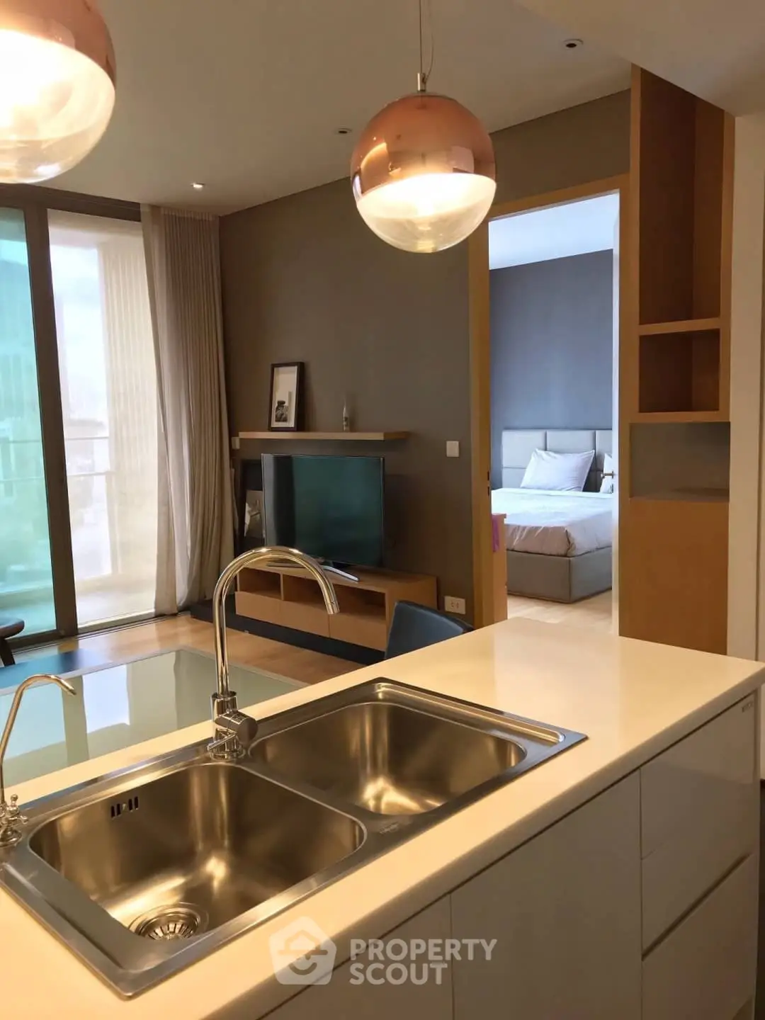 Modern open-plan kitchen with sleek fixtures and view into cozy bedroom