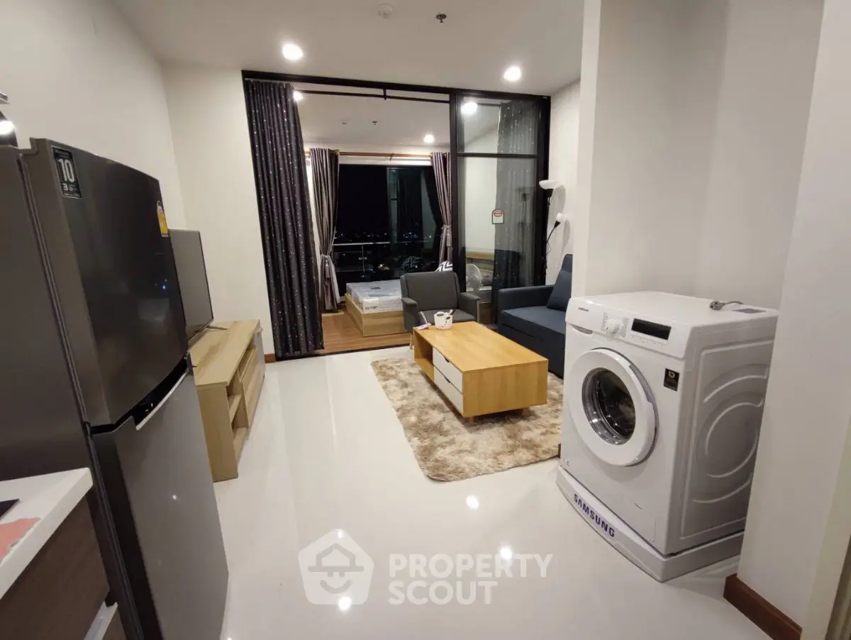 Modern apartment interior with open layout, featuring washing machine and stylish furniture.