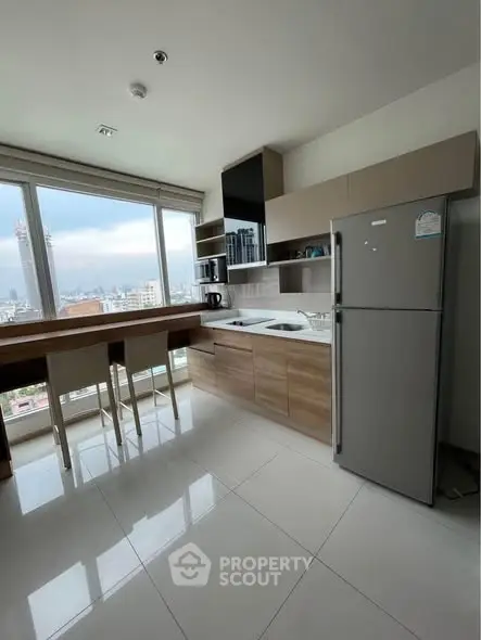 Modern kitchen with city view, featuring sleek cabinetry and large windows.