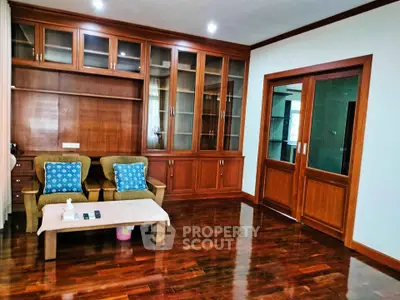 Elegant living room with wooden cabinetry and polished floors, featuring cozy seating and stylish decor.