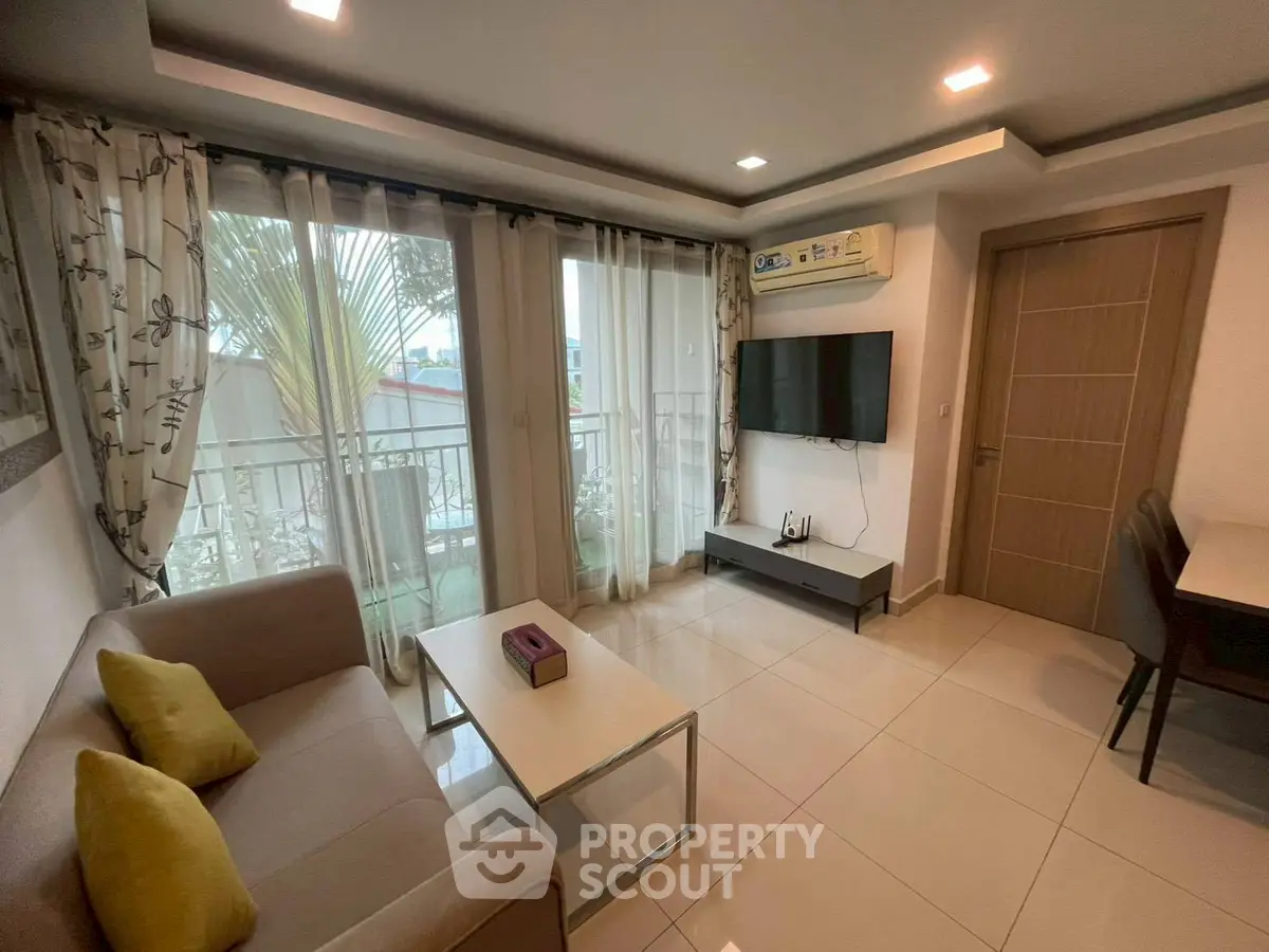 Modern living room with balcony, stylish sofa, and wall-mounted TV.