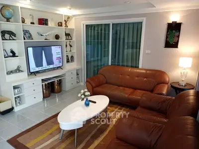 Spacious living room with leather sofas and modern decor, perfect for relaxation and entertainment.