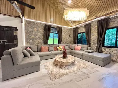 Luxurious living room with stone walls, elegant chandelier, and plush sectional sofa.