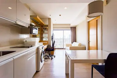 Modern apartment interior with open kitchen and city view balcony.