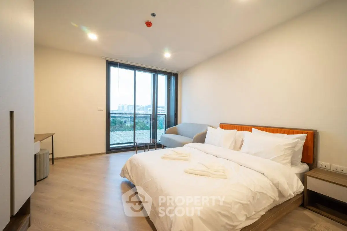 Spacious modern bedroom with large window and cozy furnishings in a stylish apartment.