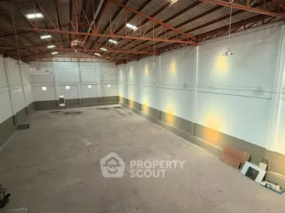 Spacious industrial warehouse with high ceilings and ample lighting, perfect for storage or manufacturing needs.