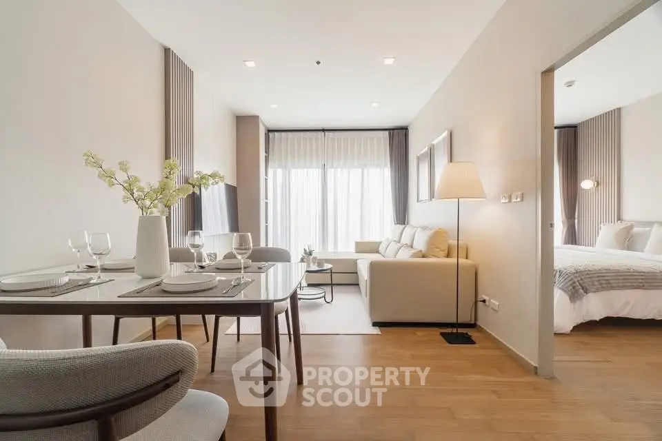 Modern open-plan living room with elegant dining area and cozy bedroom view.