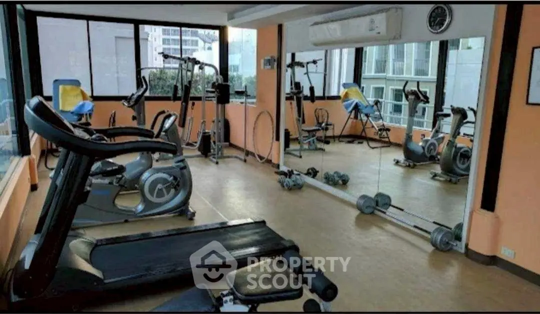 Spacious gym with modern equipment and large mirrors in a residential building.