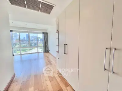 Spacious modern living room with large windows and wooden flooring offering city views.