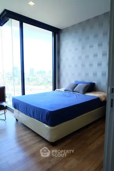 Modern bedroom with large windows offering stunning city views and stylish decor.