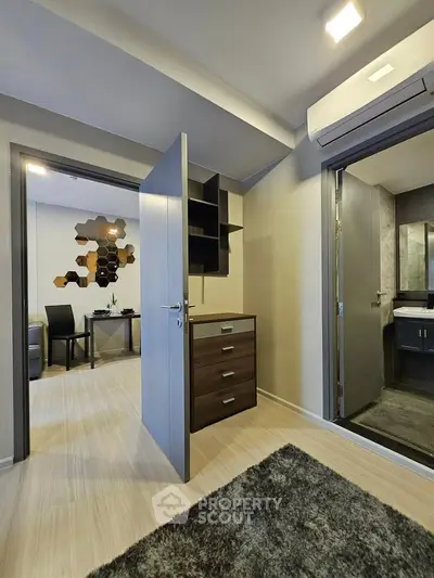 Modern apartment interior with open door leading to a stylish bathroom and study area, featuring sleek design elements.