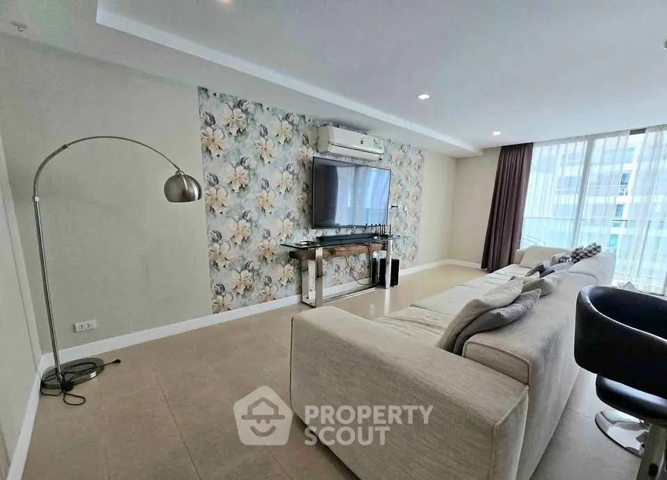 Spacious modern living room with floral accent wall and large windows