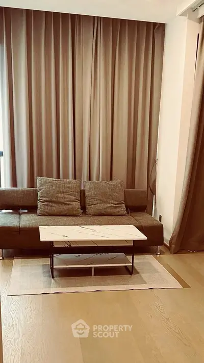 Modern living room with stylish sofa and marble coffee table, elegant curtains and wooden flooring.