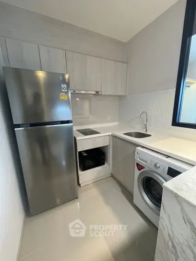 Modern kitchen with sleek appliances and washing machine in compact layout.