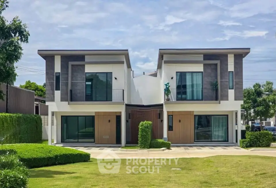 Modern duplex house with sleek design and lush green lawn, perfect for contemporary living.