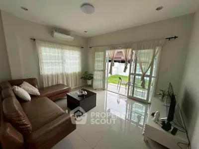 Spacious living room with leather sofa and garden view, perfect for relaxation.