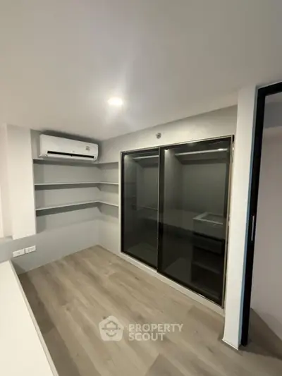 Modern room with air conditioning and sleek glass doors, perfect for storage or study space.