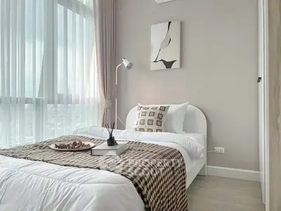 Modern bedroom with large window and stylish decor in a high-rise apartment.