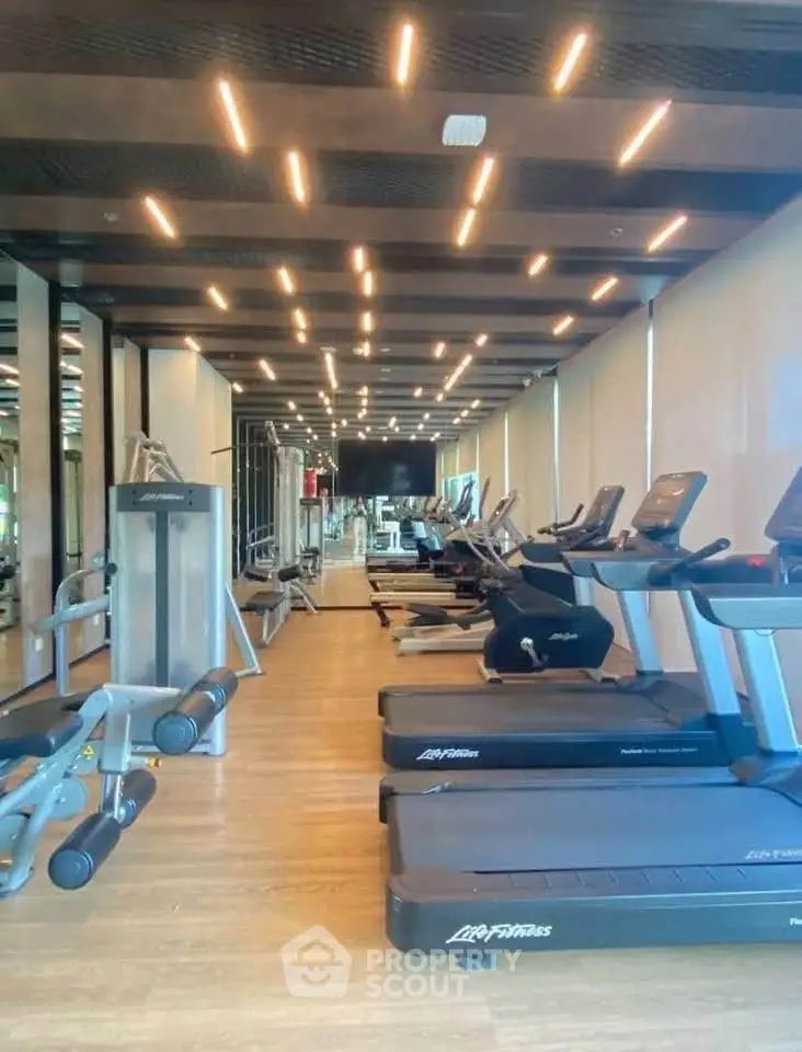 Modern gym with state-of-the-art equipment and stylish lighting in luxury residential building.