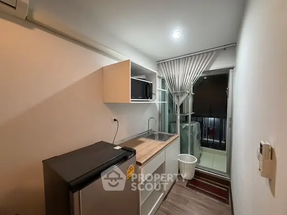 Compact kitchen with modern appliances and balcony access in urban apartment