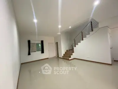 Spacious living room with gleaming tiled floors, modern lighting, and an elegant staircase leading to the upper level, perfect for stylish urban living.